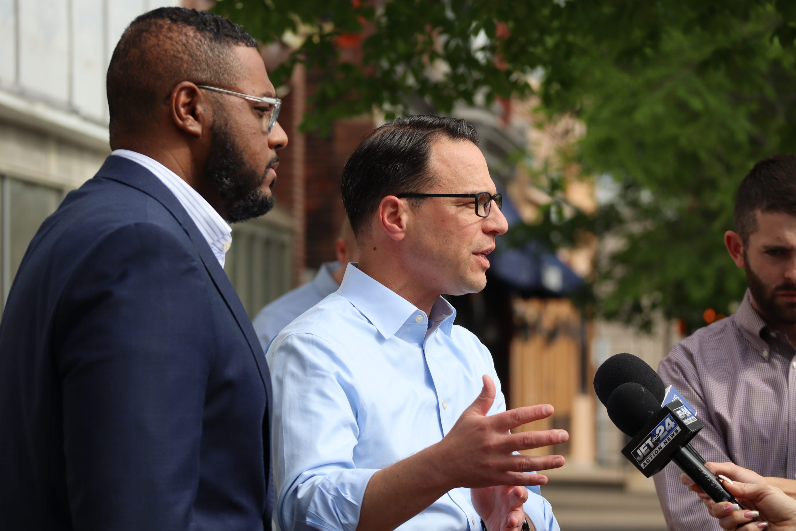 Josh Shapiro is speaking into a microphone. Austin Davis stands next to him.