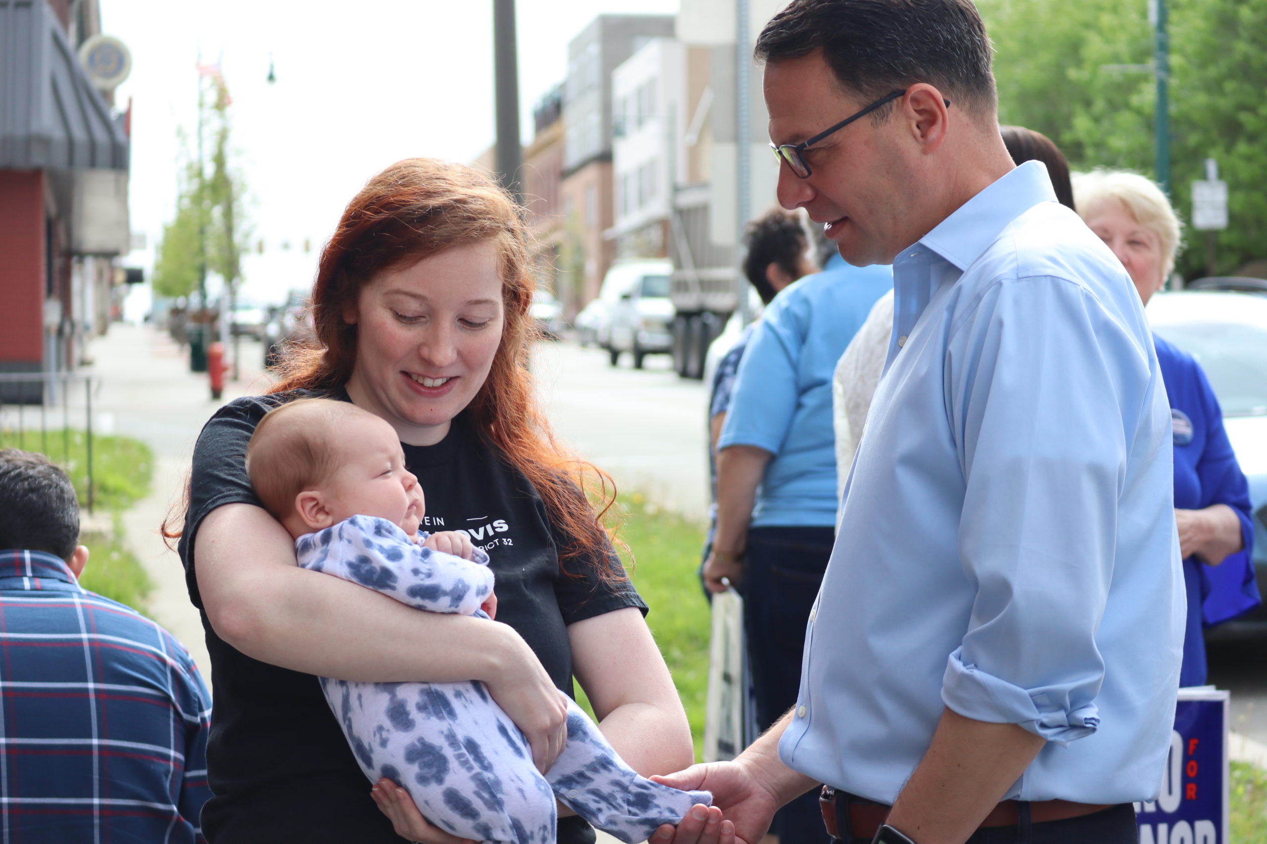 Josh greets a woman holding a baby.