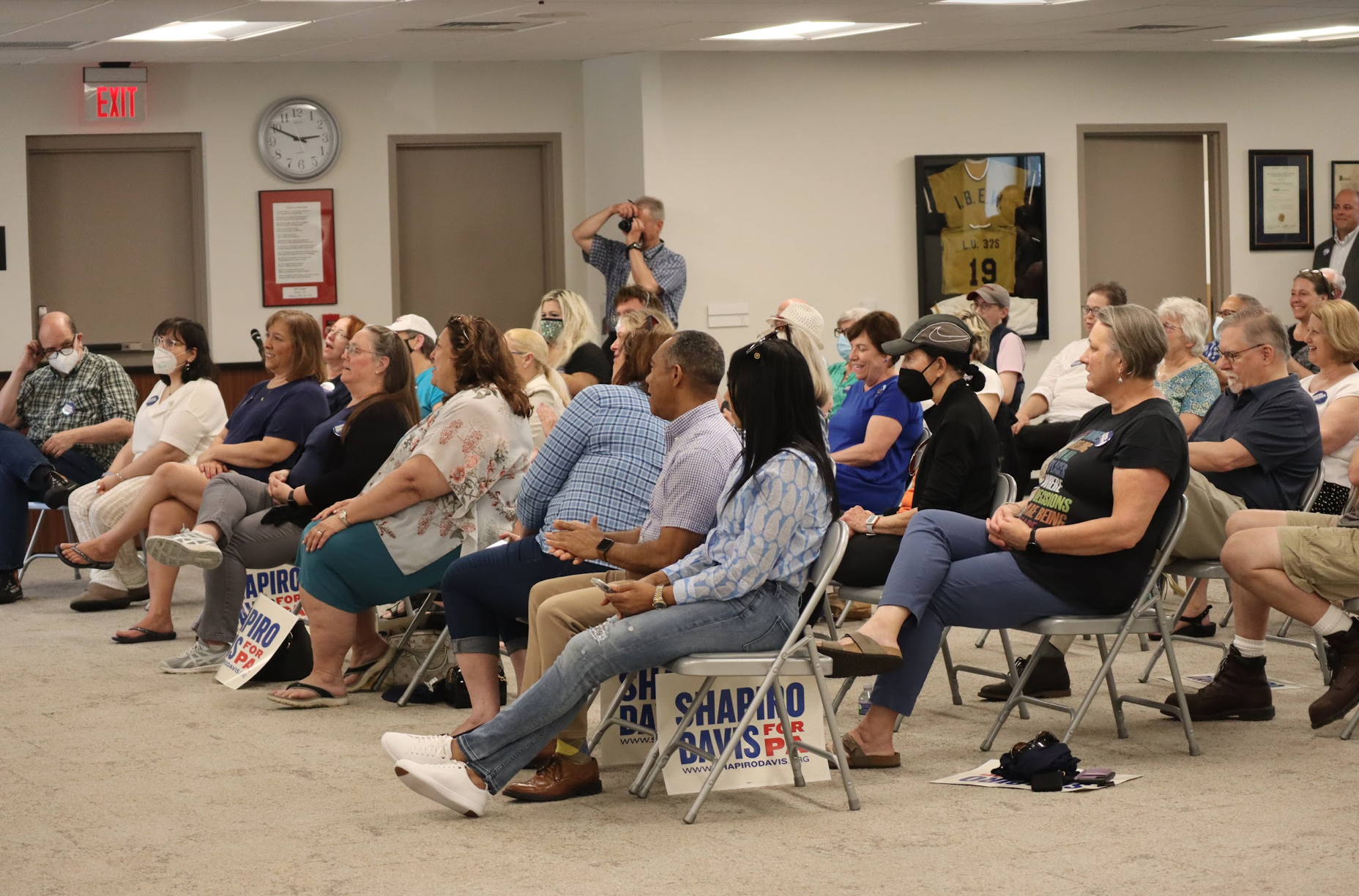 Crowd of people are sitting in chairs.